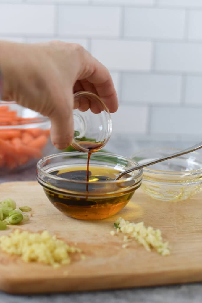 hand mixing honey and soy sauce in glass bowl