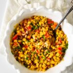 cajun corn recipe in white bowl with serving spoon