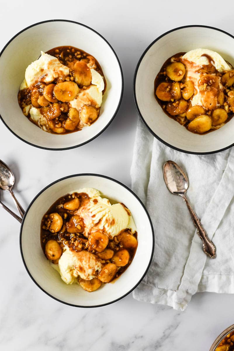 three bowls with bananas foster over vanilla ice cream