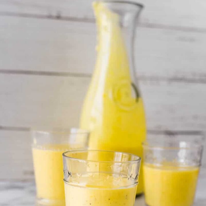 three glasses with mango lassi beside pitcher