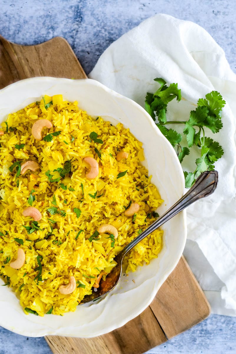 white bowl on wooden board filled with indian lemon rice 