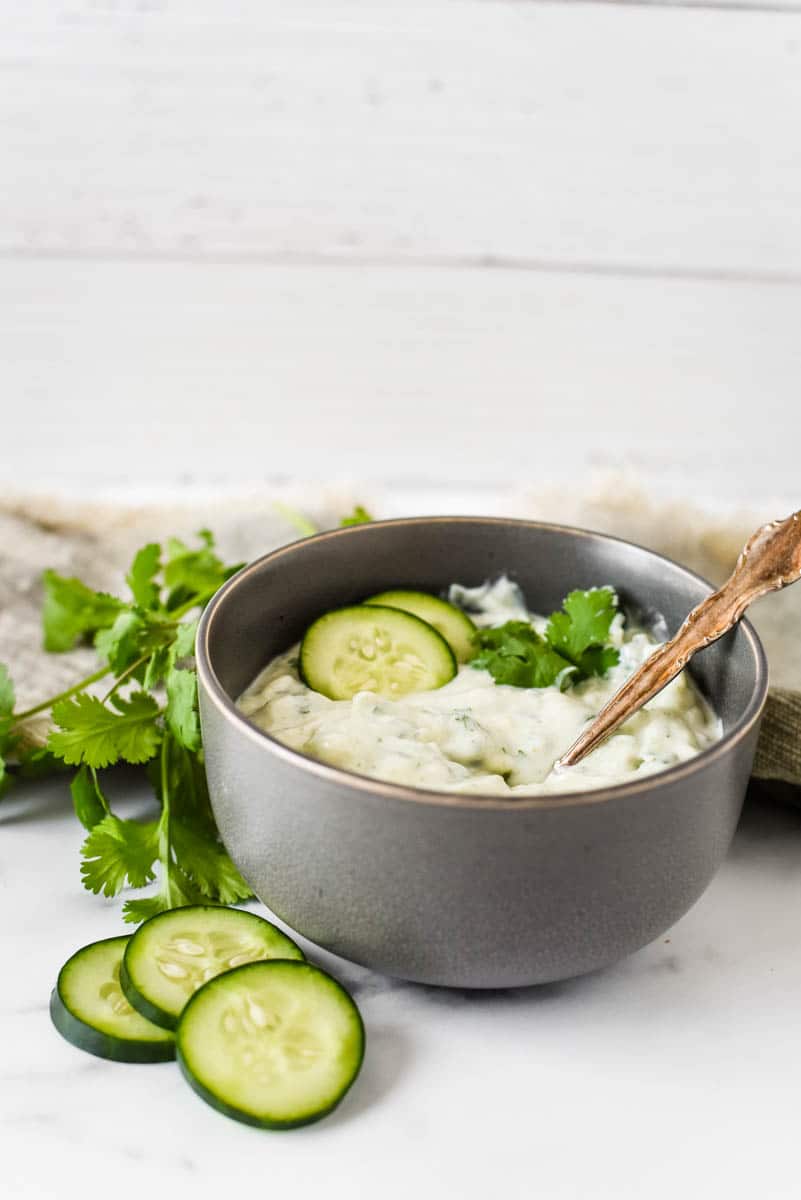 grey bowl with cucumber raita with cucumbers 