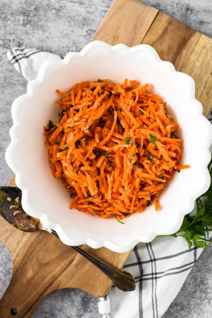 white bowl with shredded carrot salad and lemon dijon vinaigrette dressing 