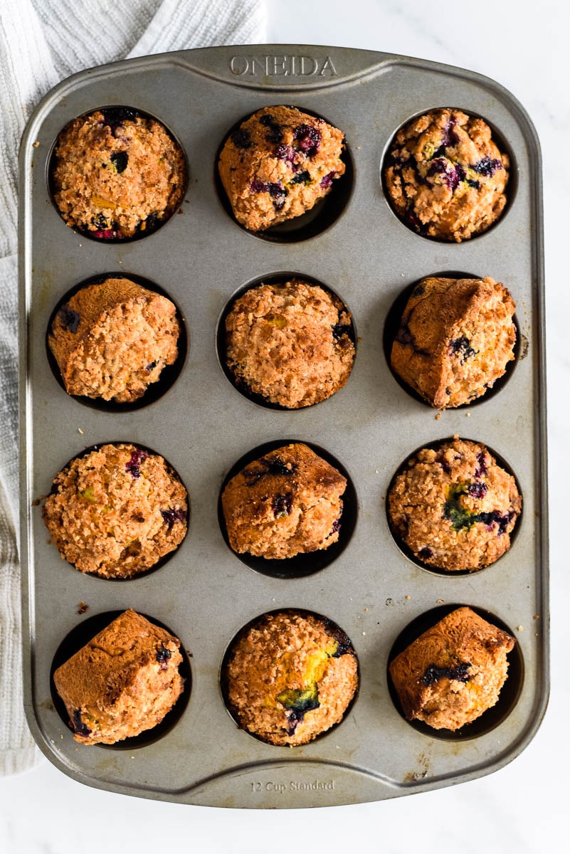 muffin pan with 12 blueberry sourdough muffins turned at various angles