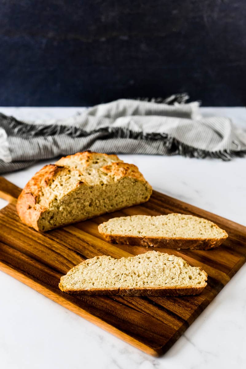 sourdough irish soda bread loaf on cutting board with two slices beside it