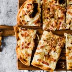 cut wedges of french bacon and onion tart on wooden cutting board