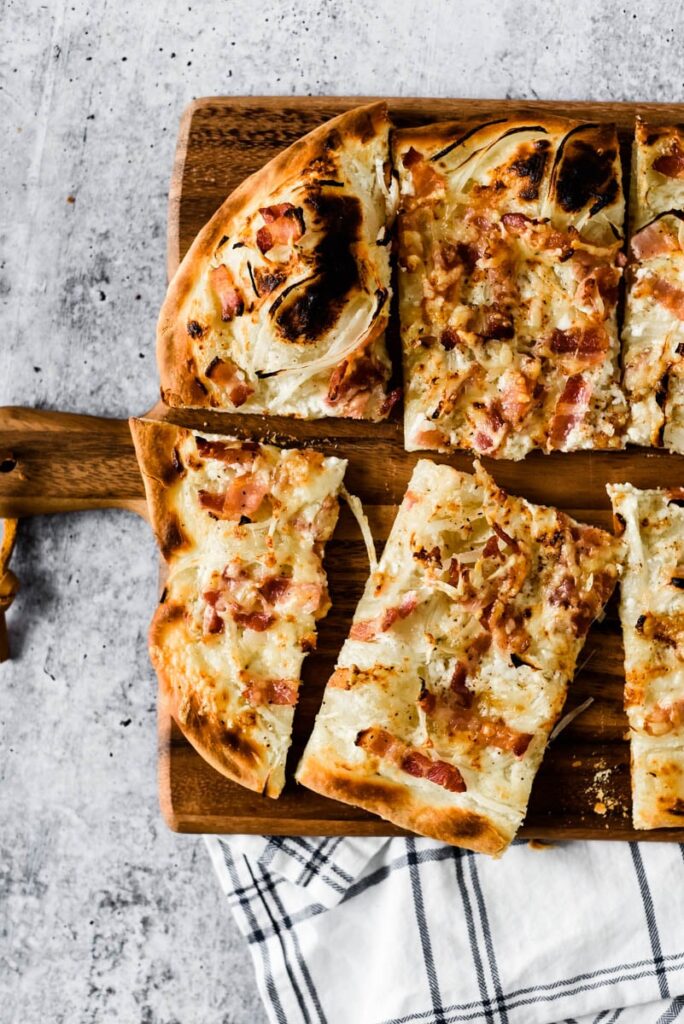  cut wedges of french bacon and onion tart on wooden cutting board 