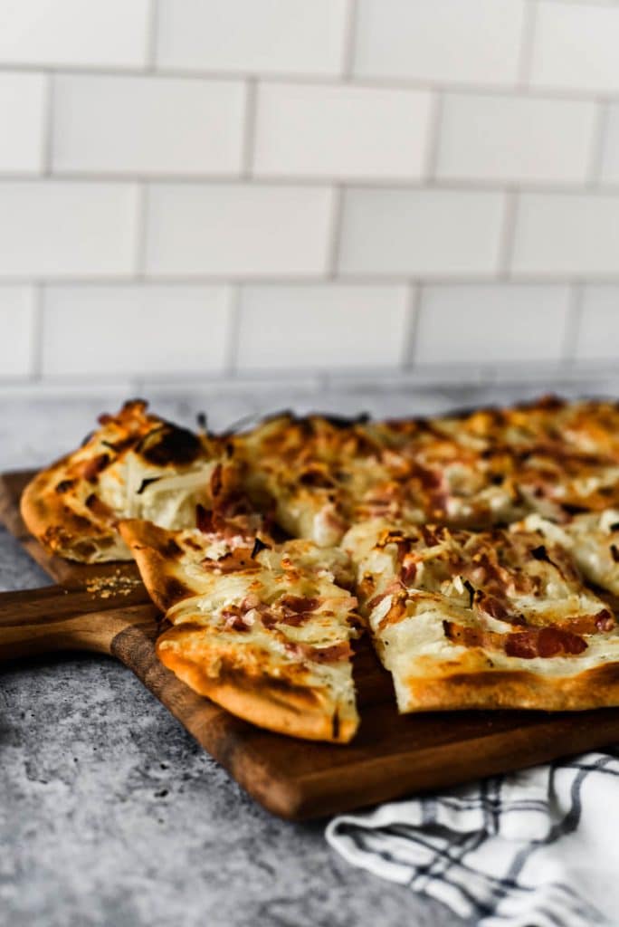 french bacon and onion tart on wooden cutting boar