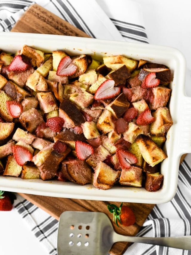 white stoneware dish filled with bread pudding, sitting on wooden board and dishcloth