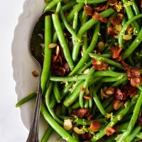 close up of green beans with bacon in white platter