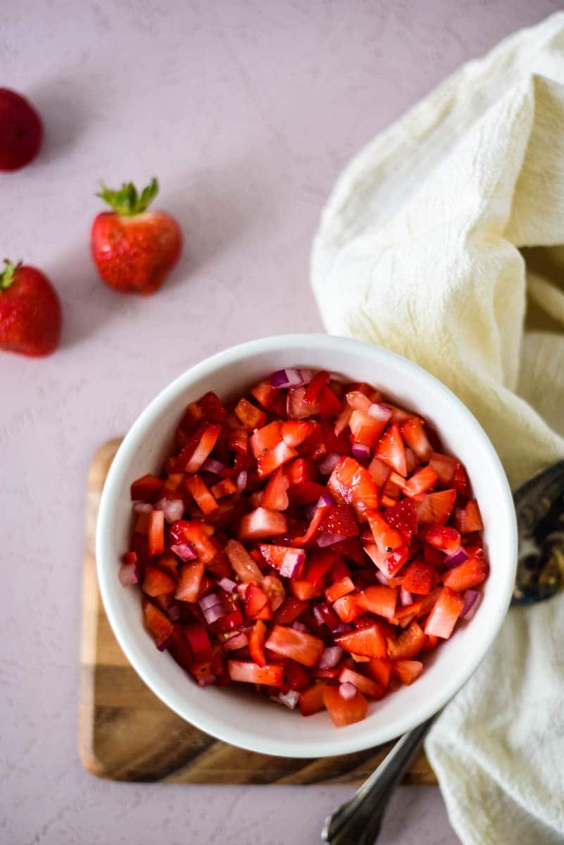 fresh strawberries in salsa in a white bowl