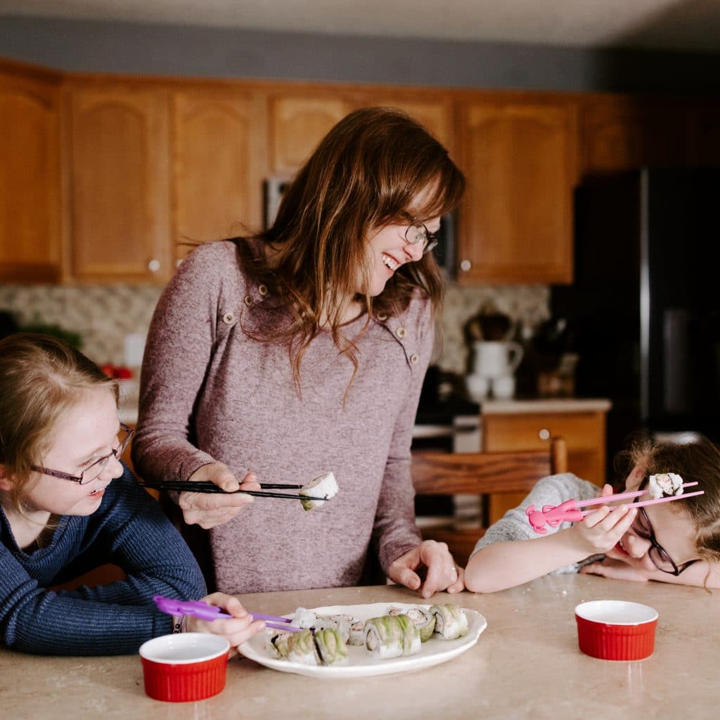 picture of a woman and children eating sushi and laughing