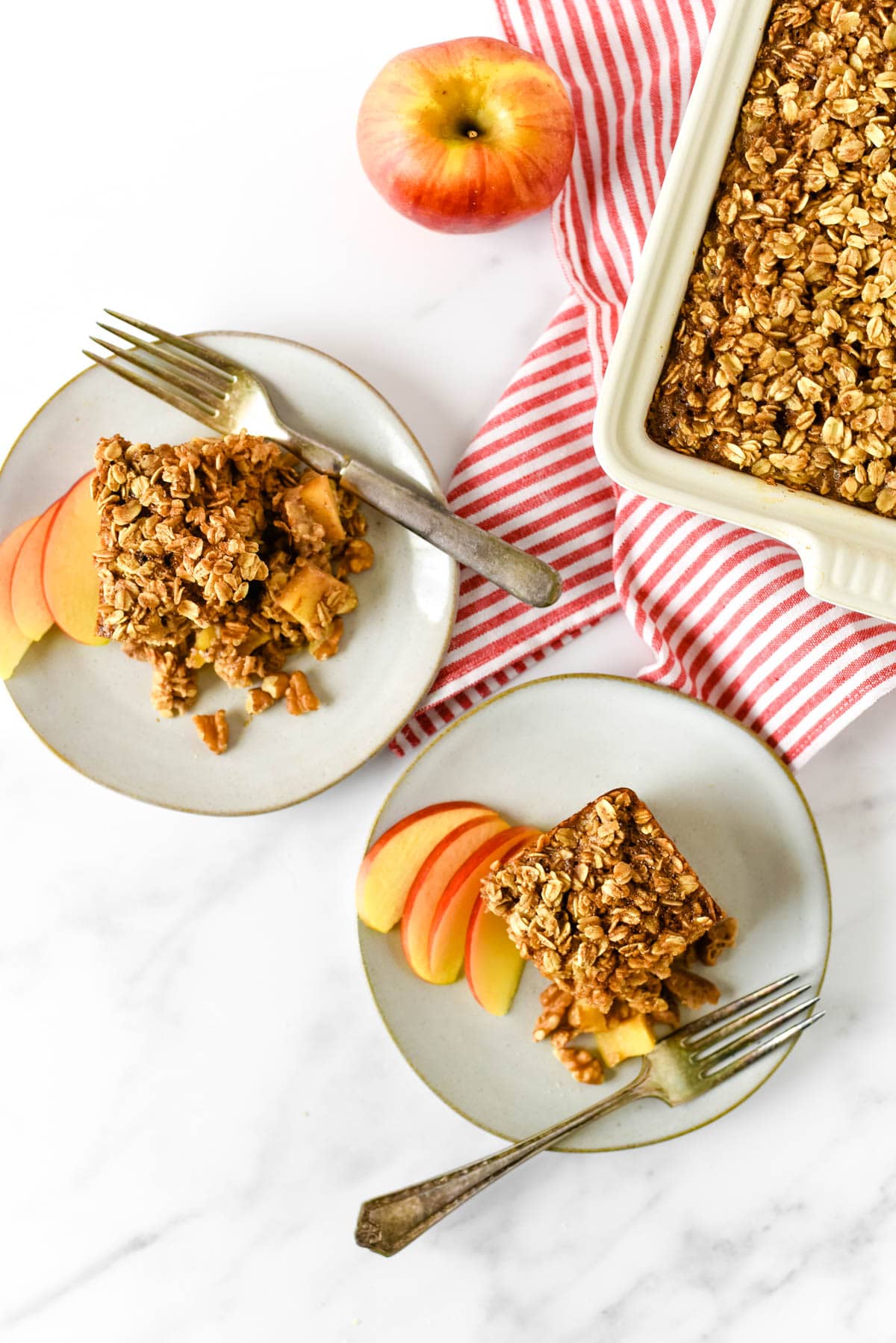 apple baked oatmeal on serving plates with dish behind