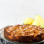 pear almond cake on platter with pears behind