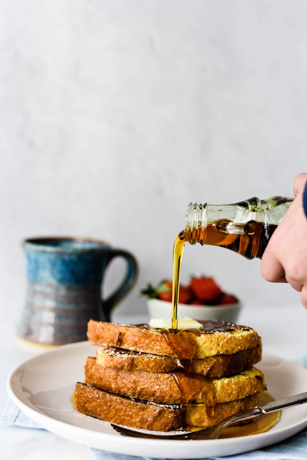 maple syrup being poured on stack of french toast