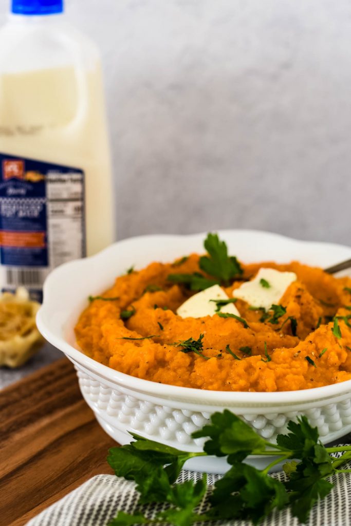 white serving bowl with mashed sweet potatoes  and  AE dairy bottle of milk behind