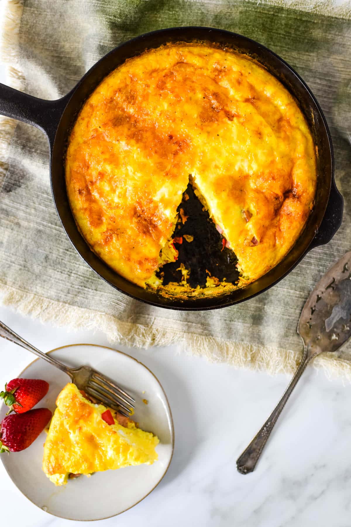 overhead view of cast iron skillet with frittata and small plate beside