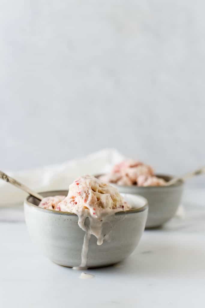 two bowls of strawberry ice cream with spoons