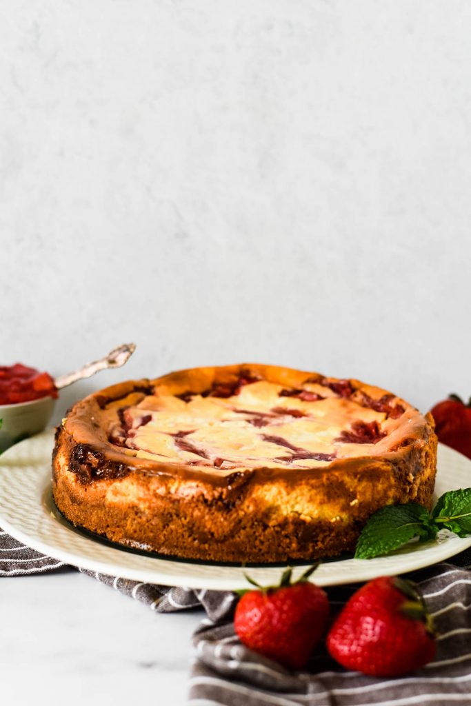 whole strawberry swirl baked cheesecake on plate