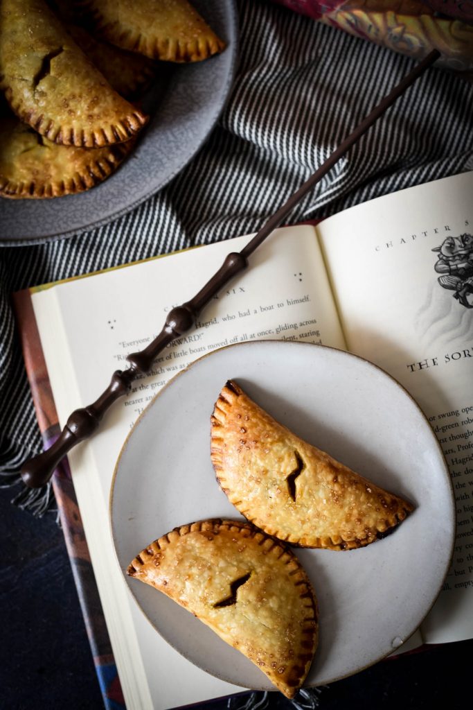 two pumpkin pasties on plate with book and wand
