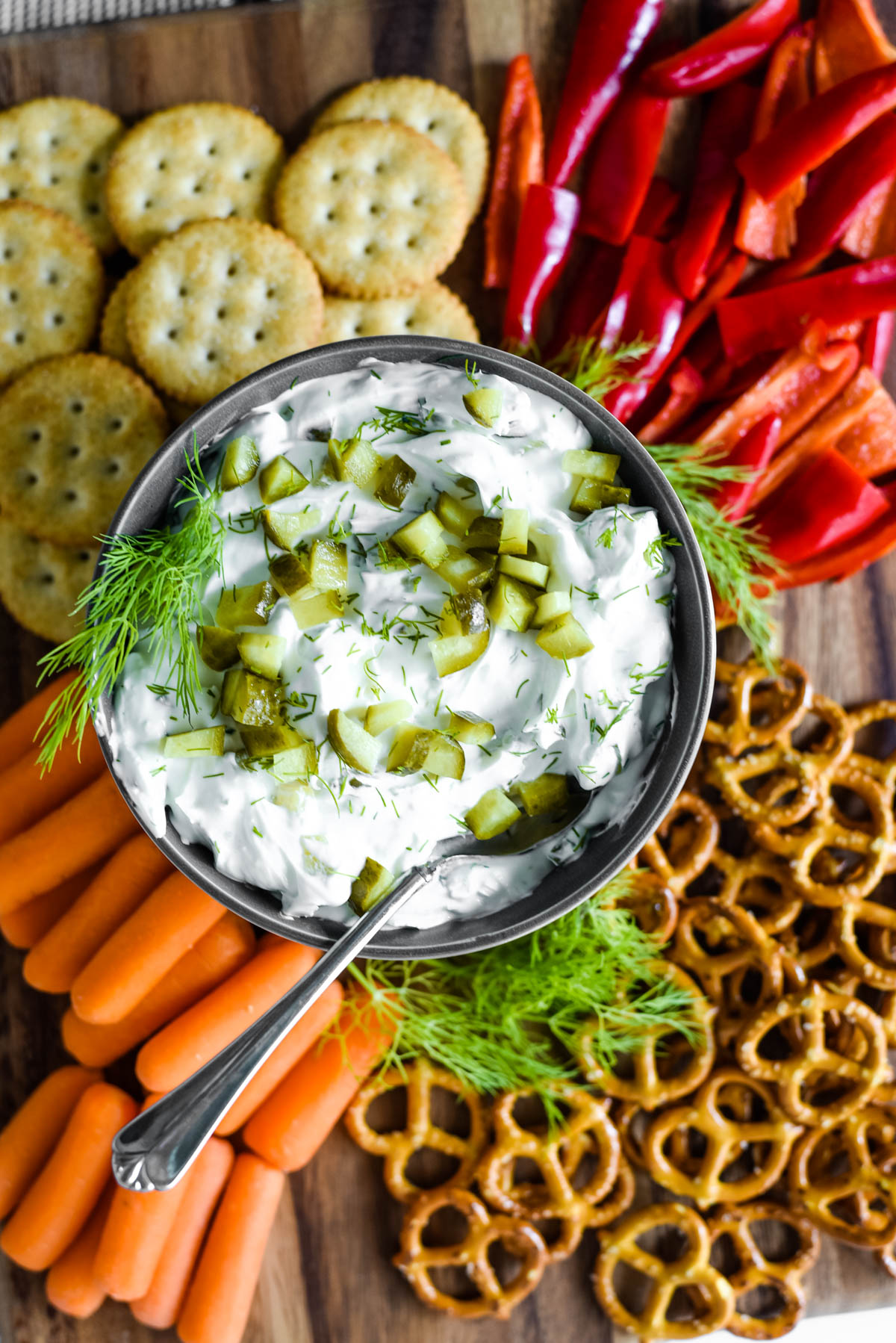 pickle dip in bowl surrounded by crackers and veggies