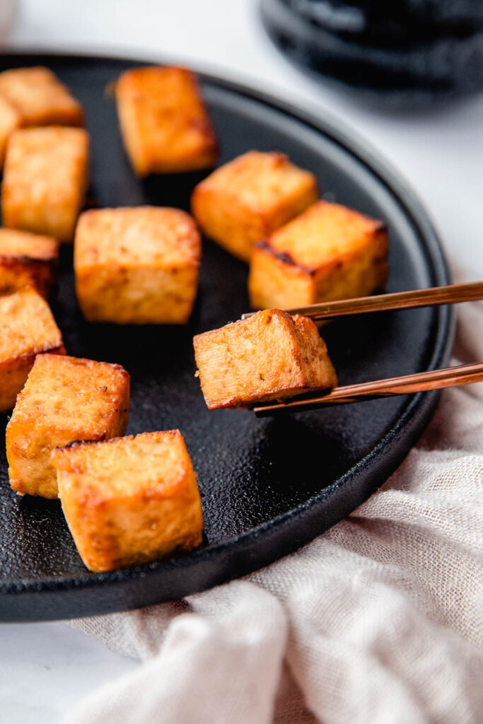 chopsticks holding piece of tofu