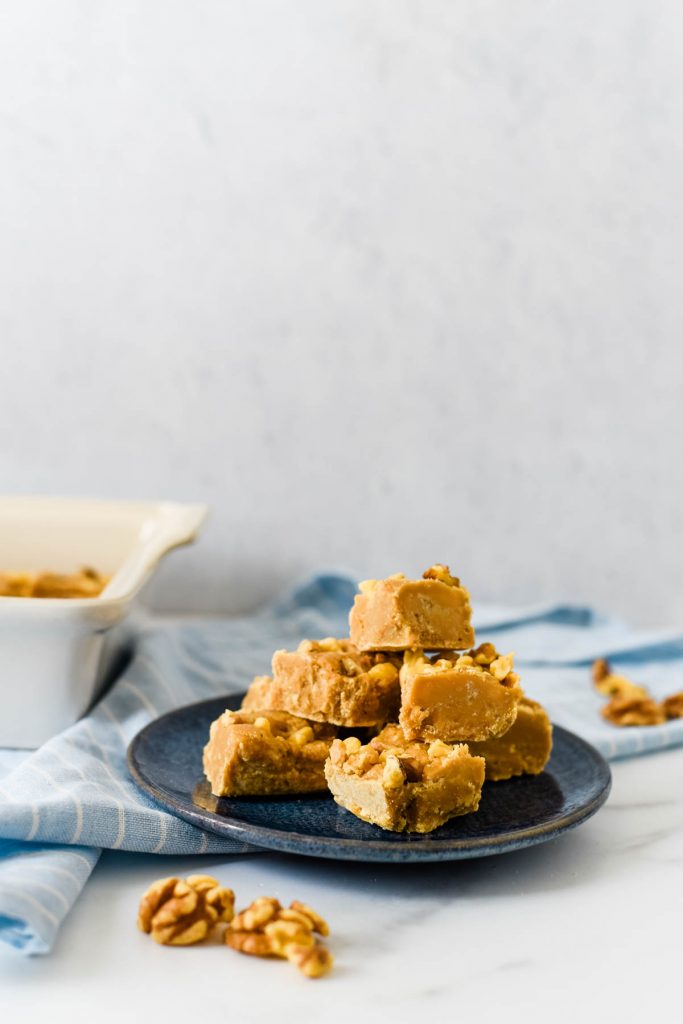 maple walnut fudge on plate with dish behind