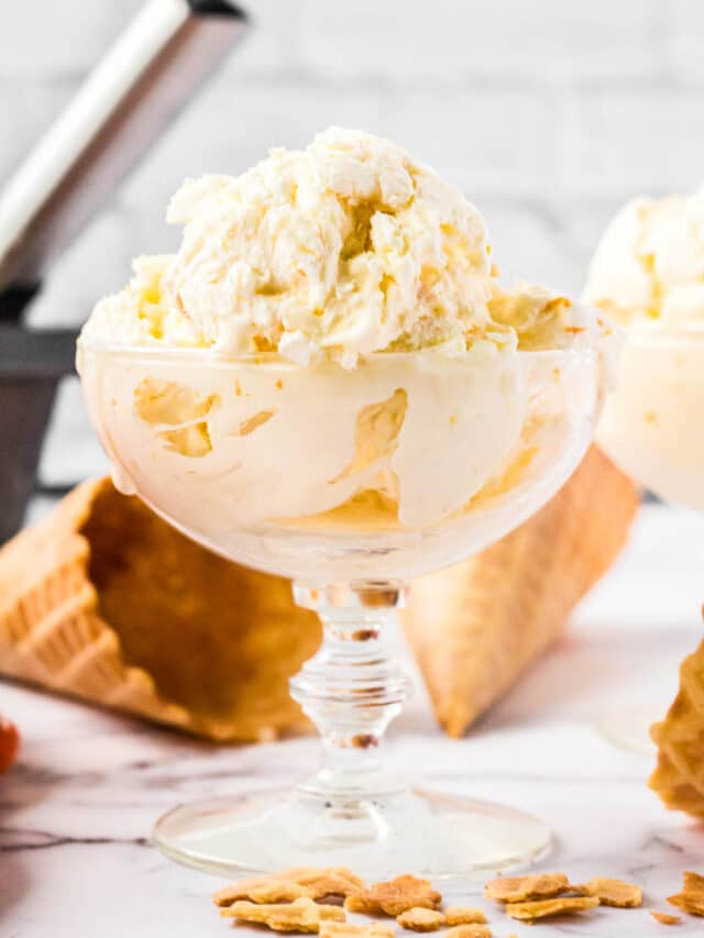 orange ice cream in glass dish with cones and pan behind