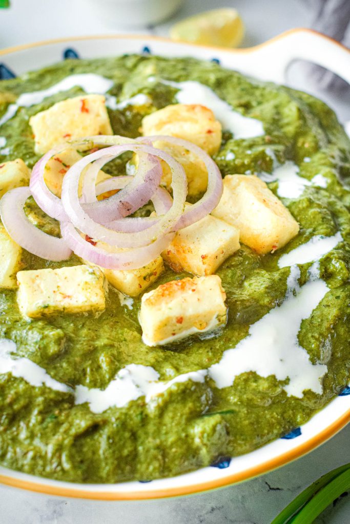 palak paneer in bowl with cream and onions