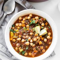 lentil and chickpea soup in bowl next to pot and spoon