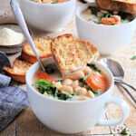 tuscan kale soup in white mug with toast and spoon on top