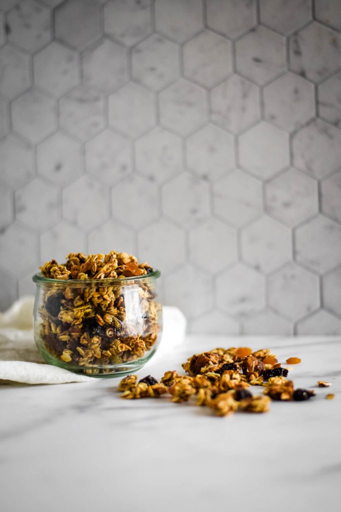 jar with homemade granola with some sprinkled on counter
