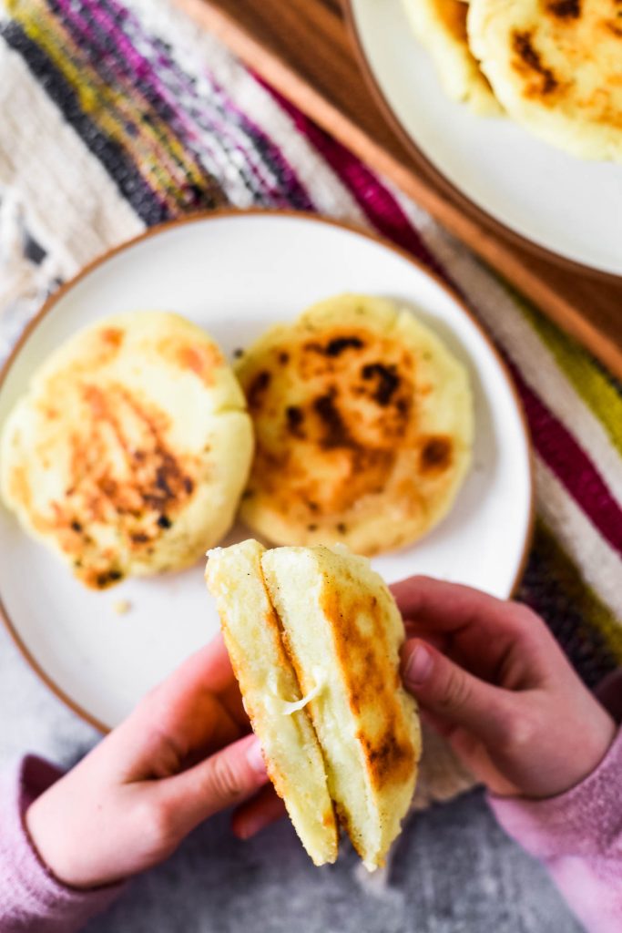 girls hand pulling apart arepa con queso