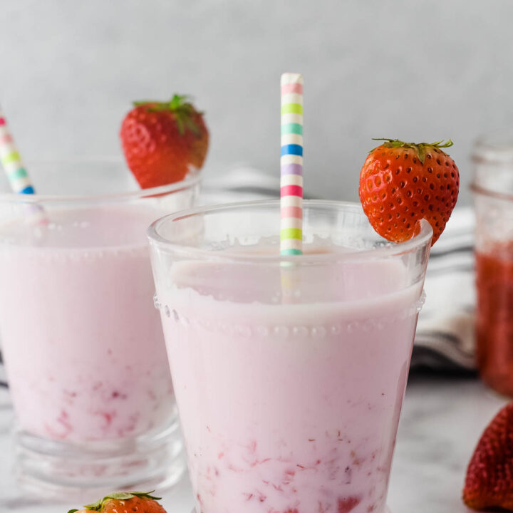 strawberry milk in a glass with strawberries and striped straw