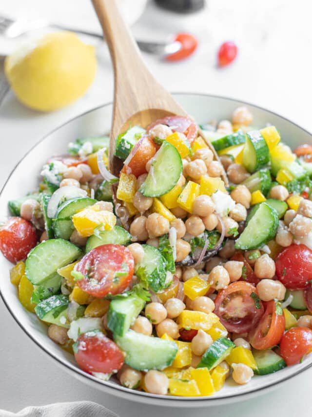 wooden spoon showing closeup of chickpea cucumber and tomato salad