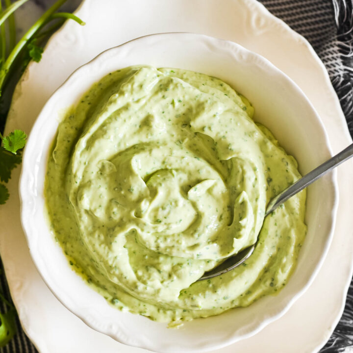 overhead image of avocado sauce in white bowl with spoon