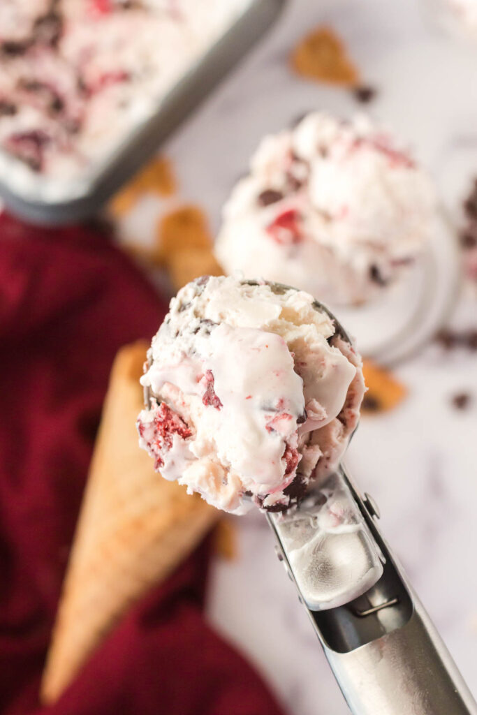 ice cream scoop with scoop of cherry chip ice cream over cone