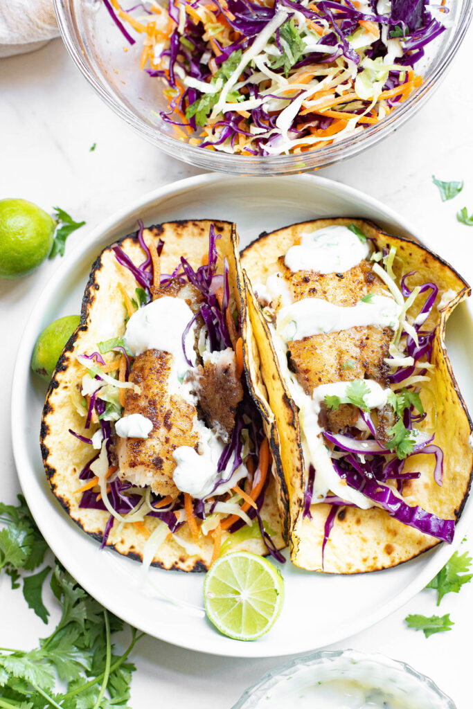 plate with two fish tacos with slaw and dressing