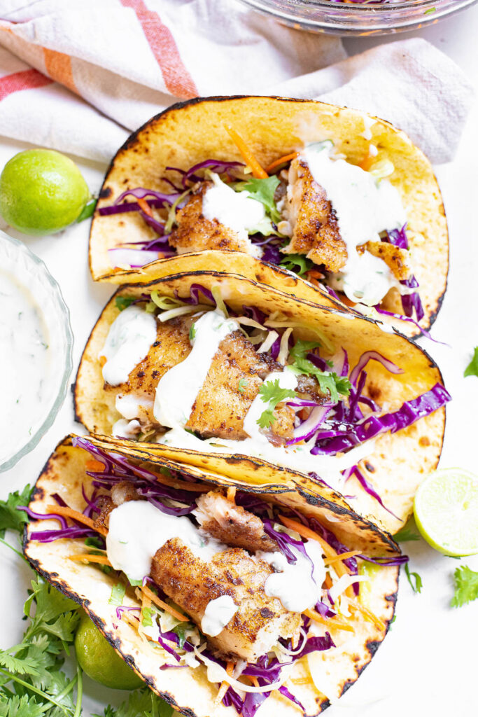 three fish tacos together with dressing and slaw