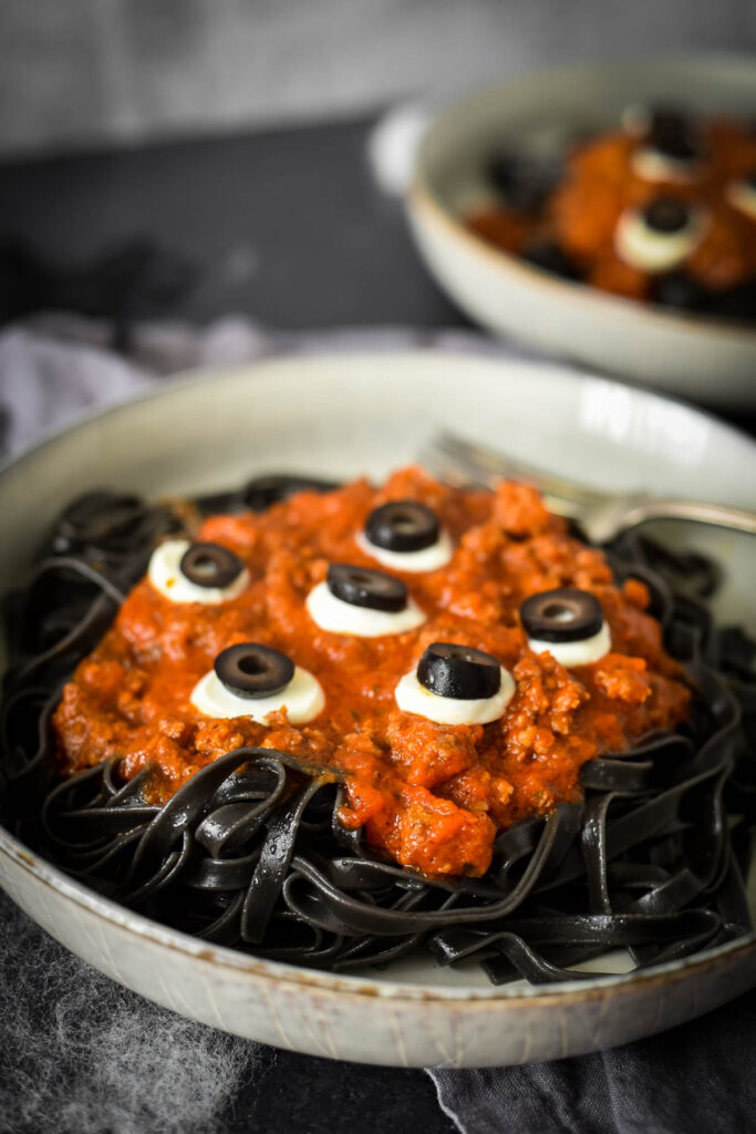 close up of halloween pasta in bowl with olive and cheese for eyes