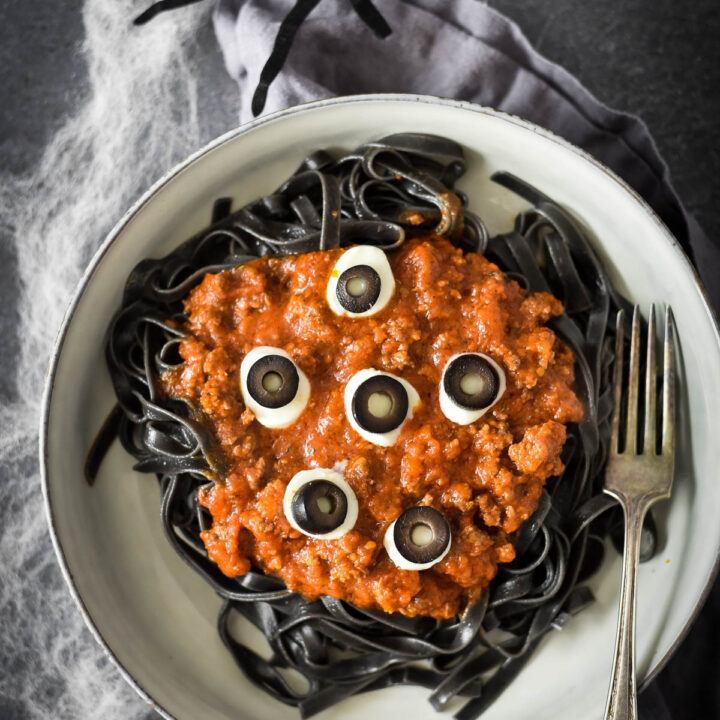 overhead view of bowl of halloween pasta with fake spider and spiderwebs
