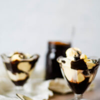 two glass dishes with vanilla ice cream and hot fudge sauce