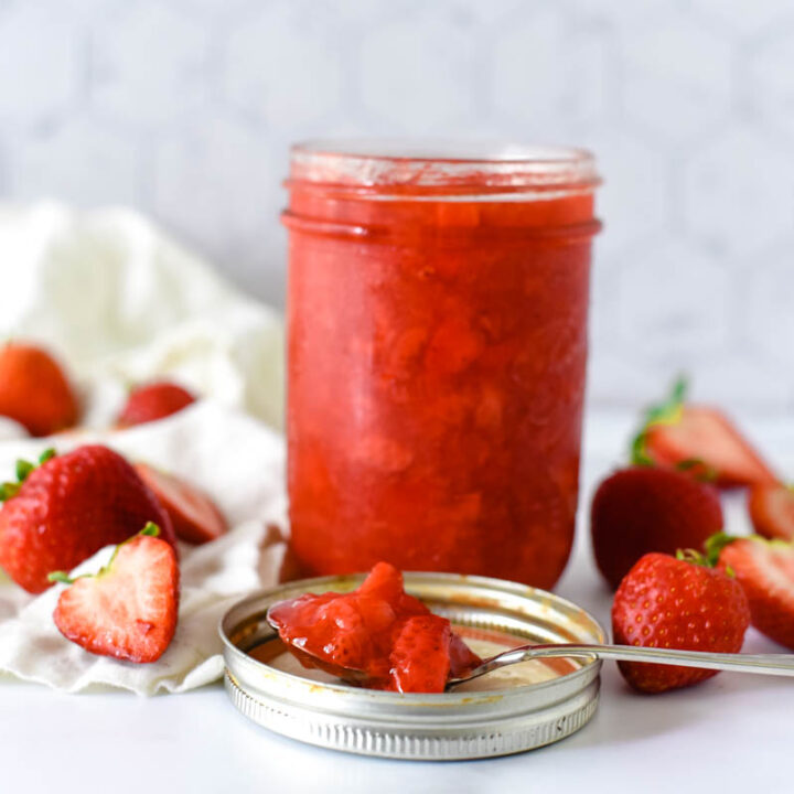 small mason jar with strawberry topping surrounded by strawberries