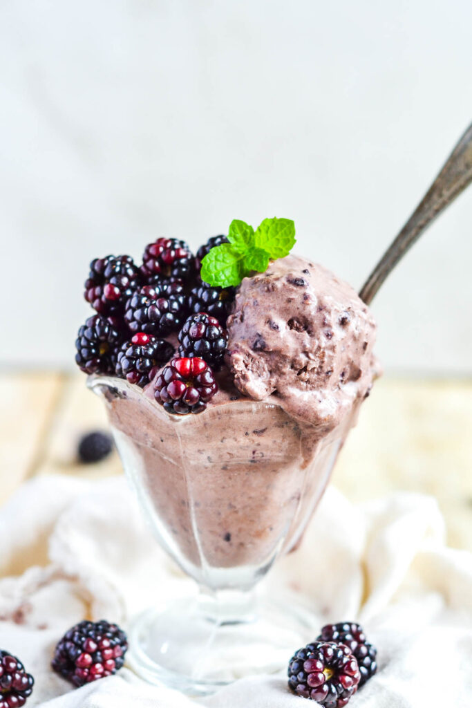 ice cream in glass dish with blackberries and mint leaves on top