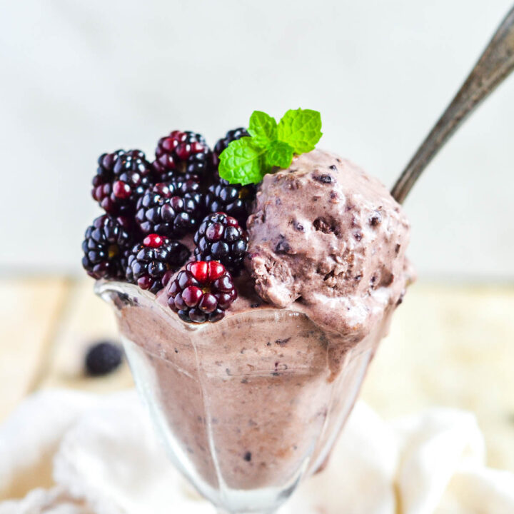 ice cream in glass dish with blackberries and mint leaves on top
