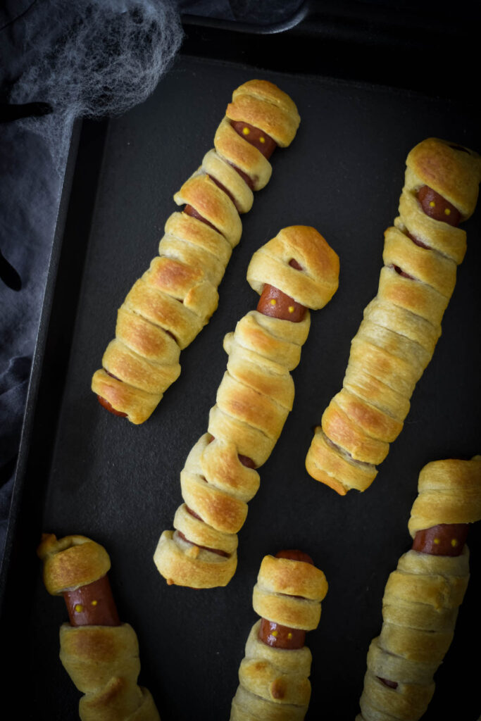 mummy hot dogs on black tray