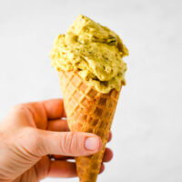 pistachio ice cream in cone being held by hand