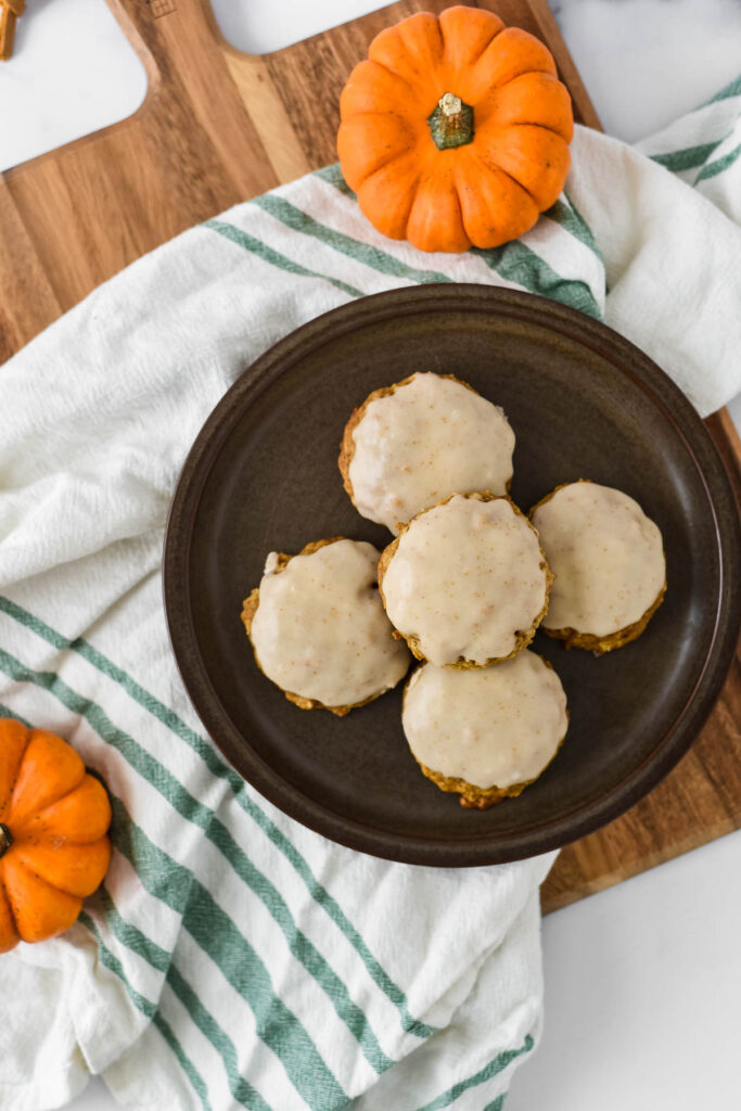 five cookies on black plate with cloth and mini pumpkins on cutting baord