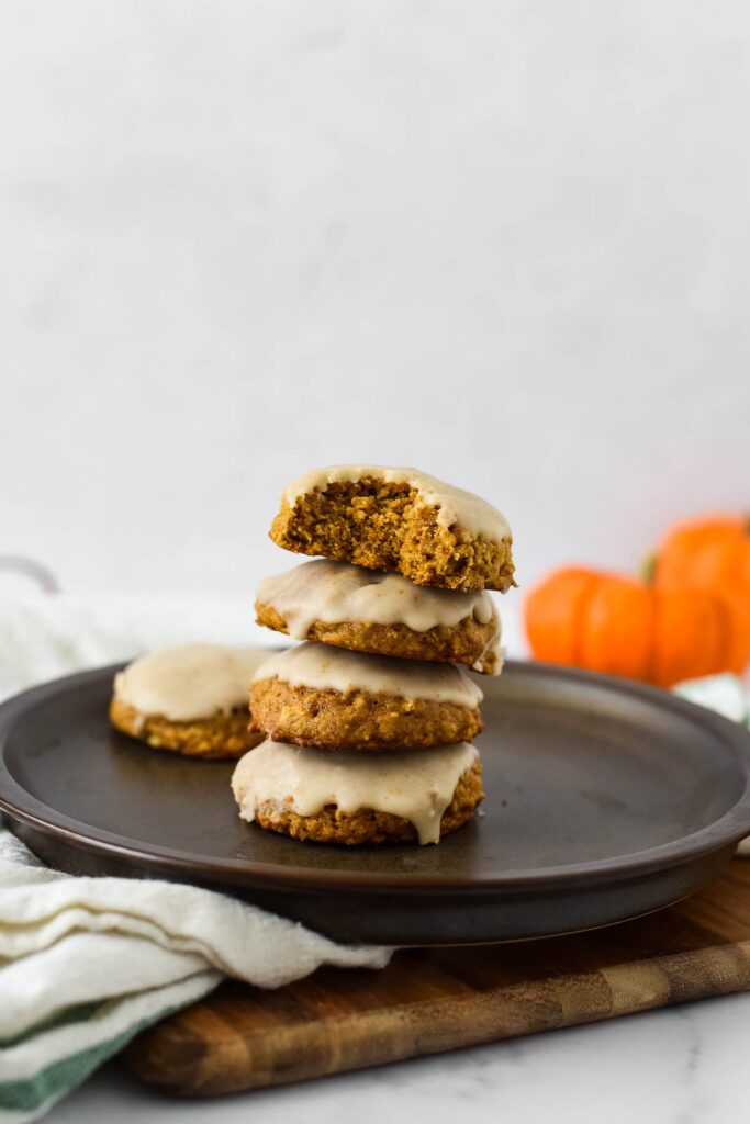 four cookies stacked on black plate with mini pumpkin behind