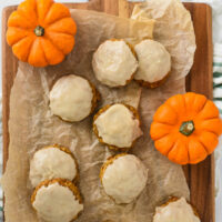 pumpkin cookies with brown butter glaze arranged on wooden cutting board with mini pumpkins